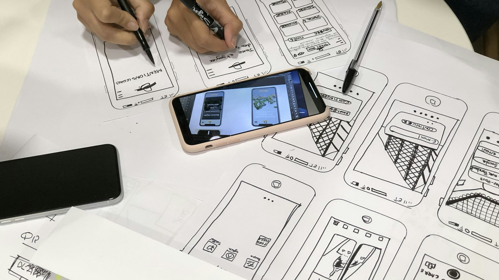 Paper mobile wireframes alongside two smartphones.