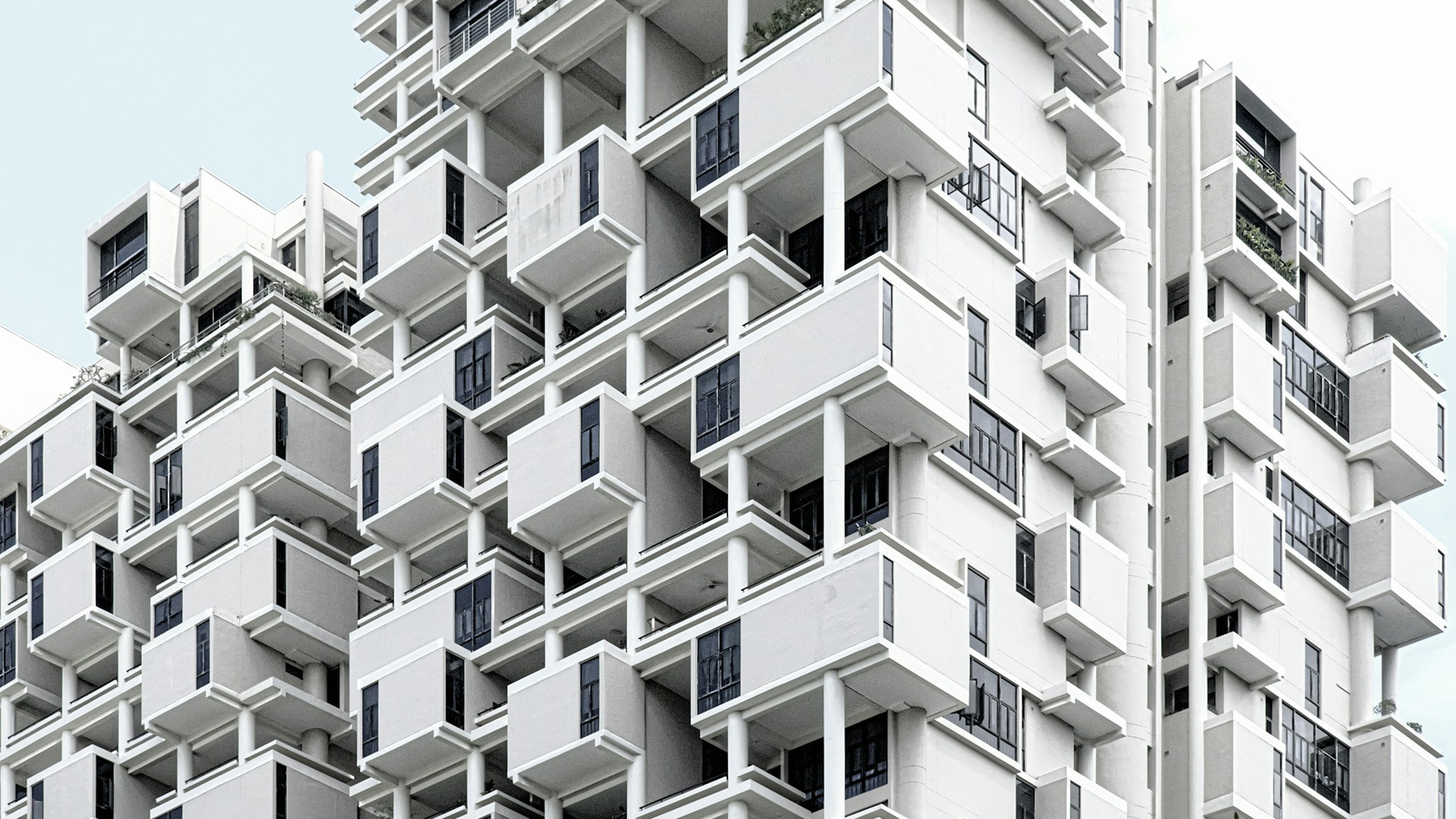 A white building facade with a repeated grid of balconies.