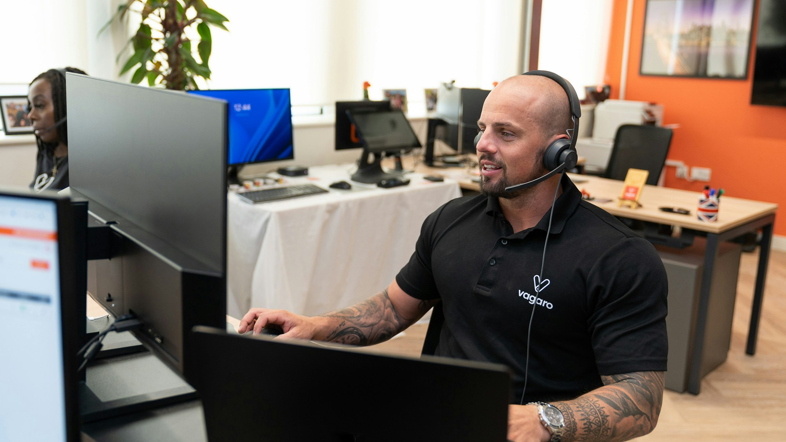 A customer-support representative wearing a headset at a multi-monitor workstation.