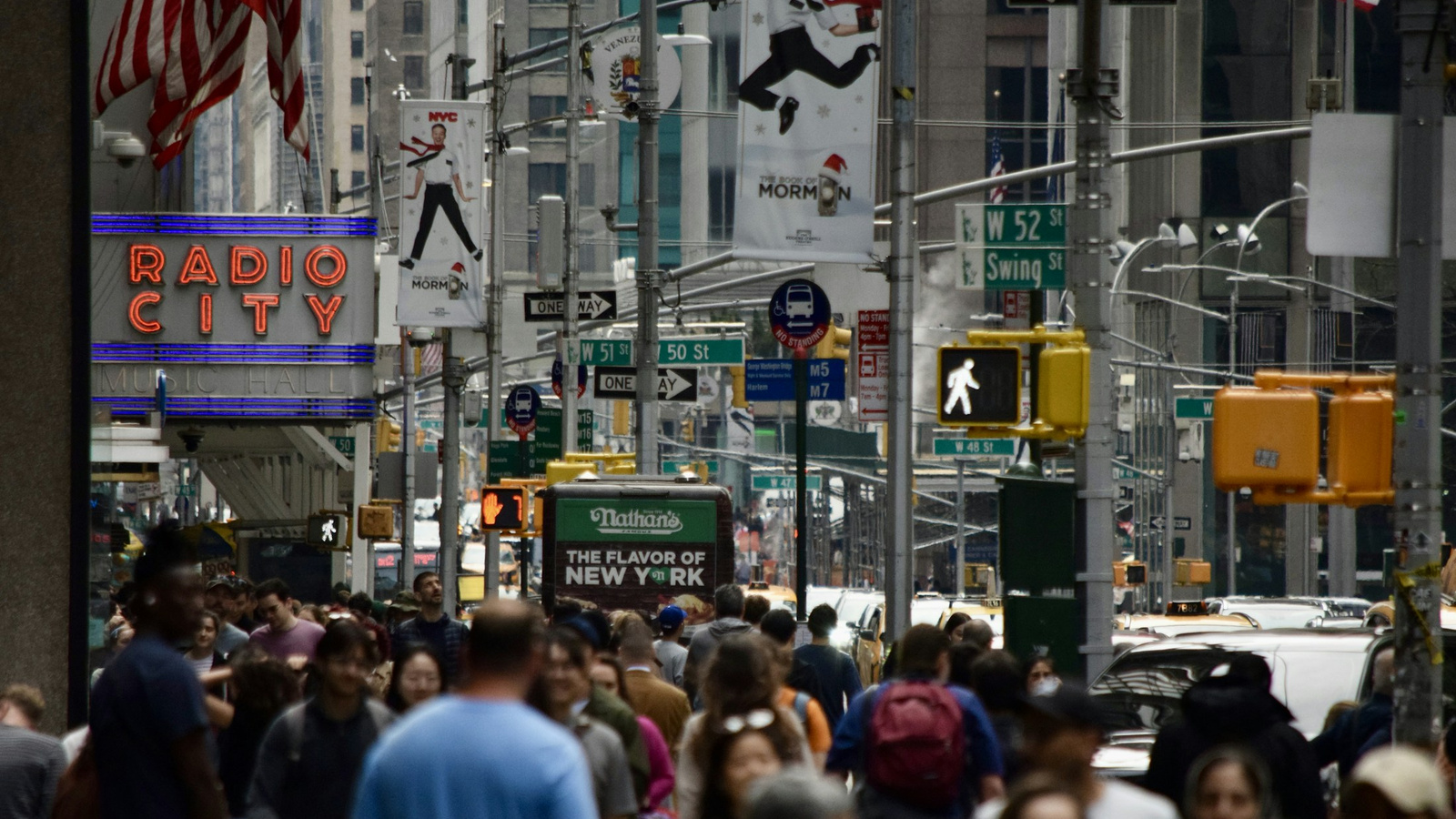 A crowded New York street with signs, traffic signals and storefronts.